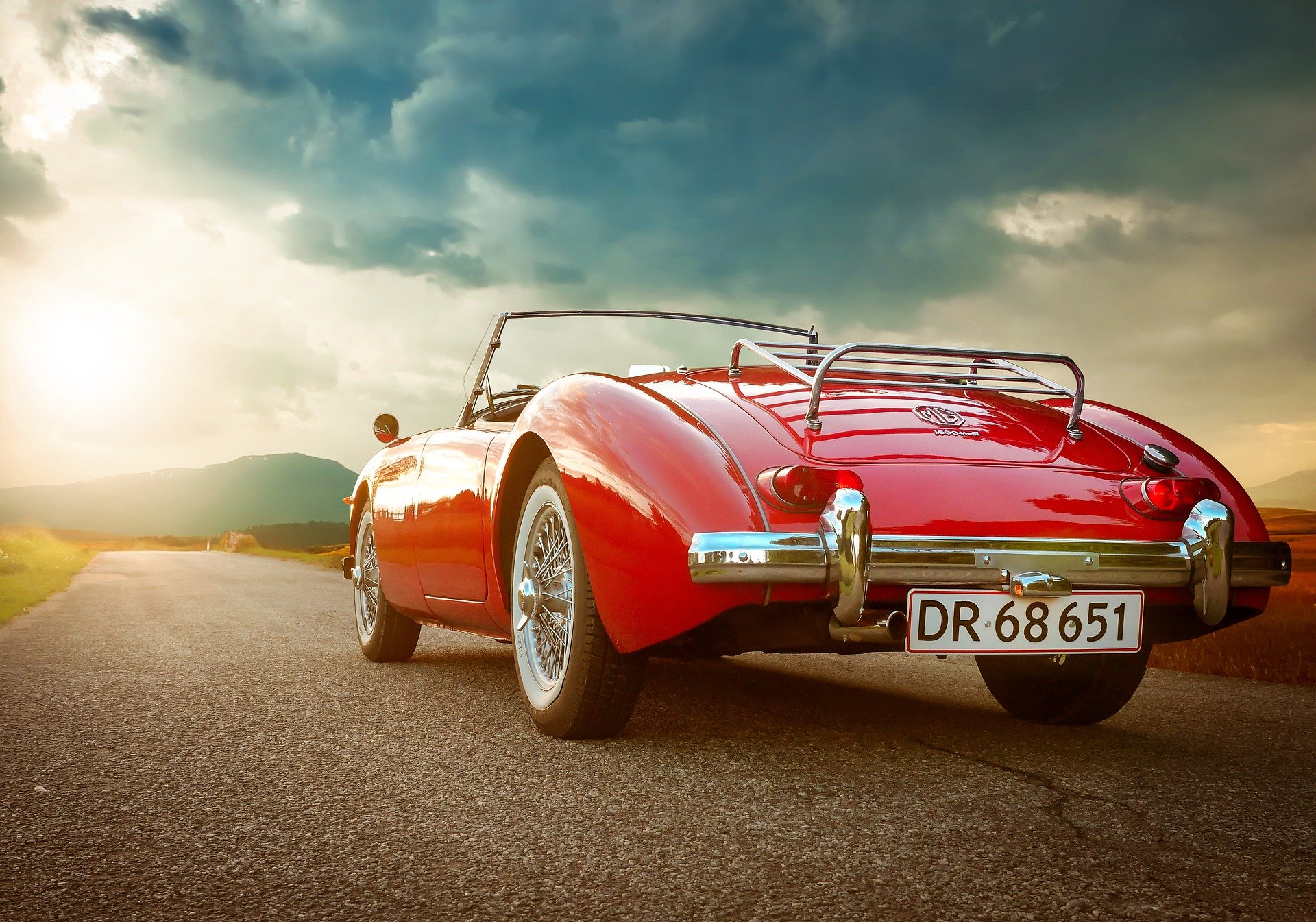 A classic red car driving into cloud.